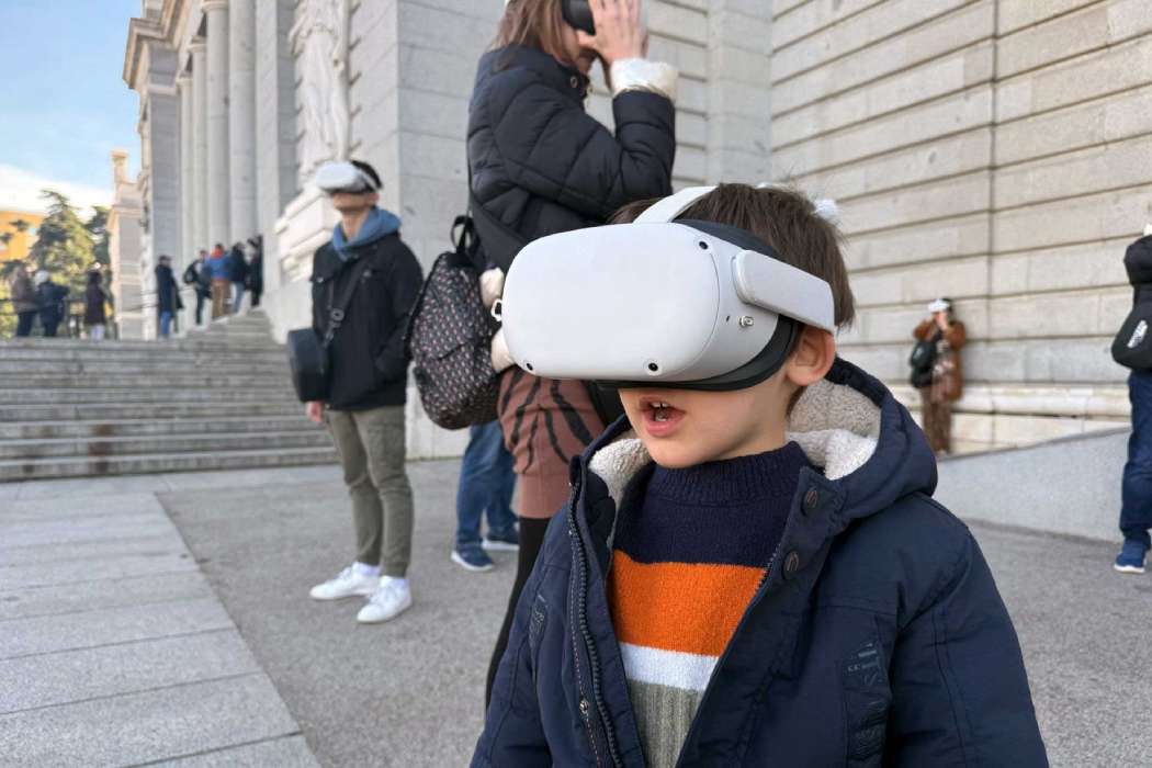 Niño con gafas de realidad virtual frente al Palacio Real de Madrid