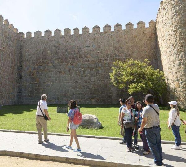 Guided tour group walking along the medieval walls of Ávila, Spain
