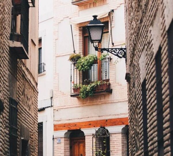 Calle típica del casco histórico de Toledo con ventana llena de flores