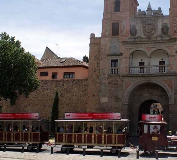 Tren turístico de Toledo pasando junto a una puerta monumental de la ciudad