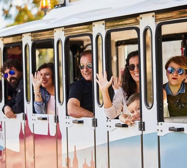 Turistas saludando desde las ventanas del tren turístico de Toledo